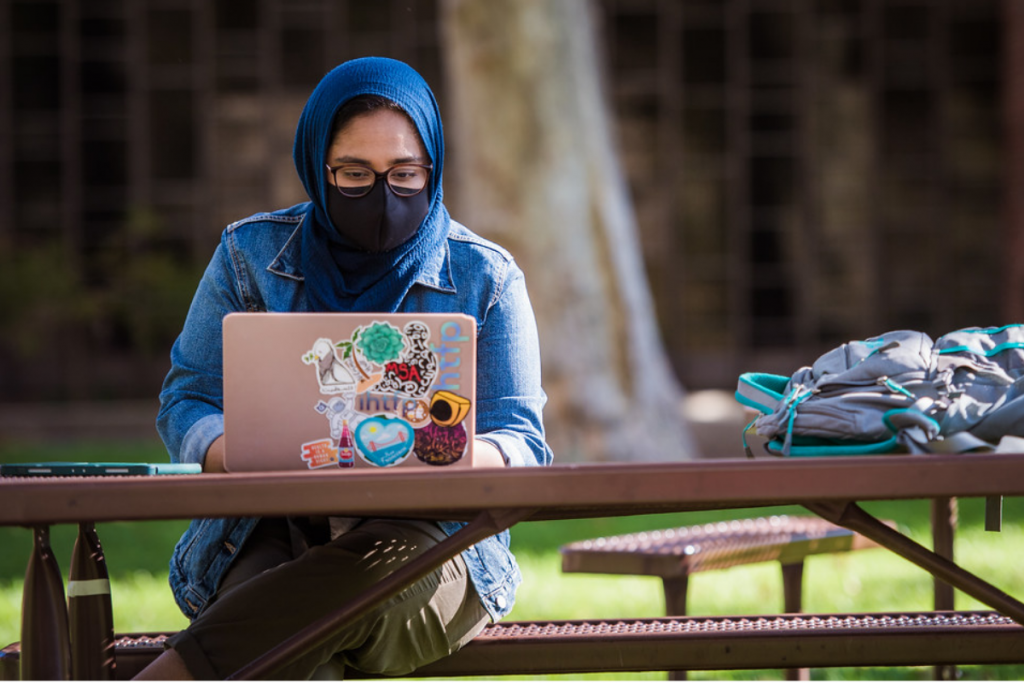 MIT student on laptop, wearing hijab, looking at screen
